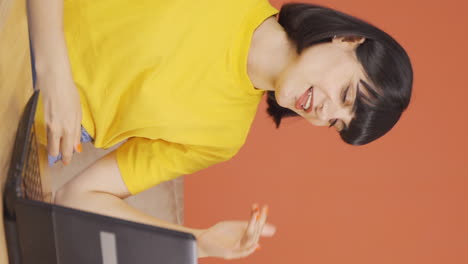 Vertical-video-of-Young-woman-looking-at-laptop-is-happy-and-dancing.